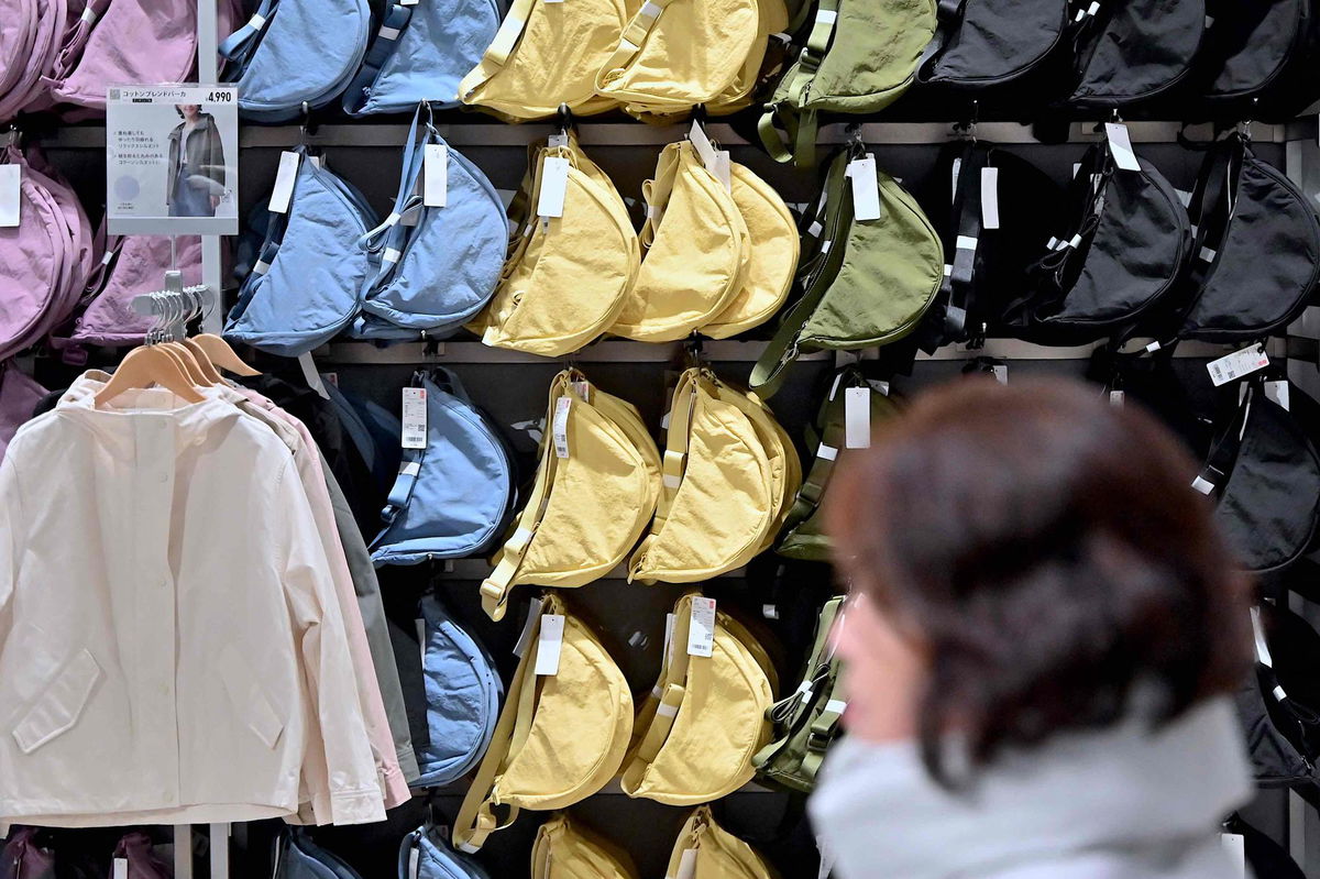 <i>Richard A. Brooks/AFP/Getty Images</i><br/>A woman walks past a rack of the viral Round Mini Shoulder Bag at a Uniqlo store in Tokyo