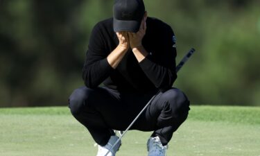 Jason Day shields himself from windswept sand at the 18th hole.