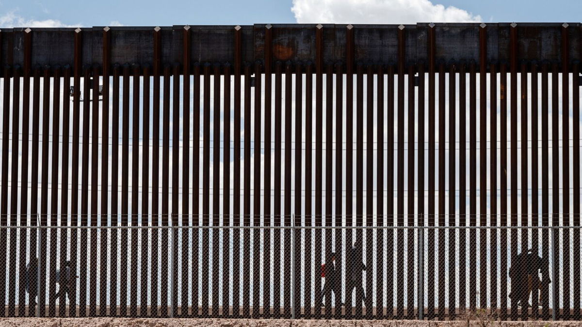 <i>Justin Hamel/Reuters via CNN Newsource</i><br/>Migrants walk along the Mexico-US border after the the Republican-backed Texas law known as SB 4 took effect on March 19.