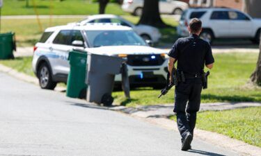 A Charlotte Mecklenburg police officer walks carrying a gun in the neighborhood where a shooting took place in Charlotte