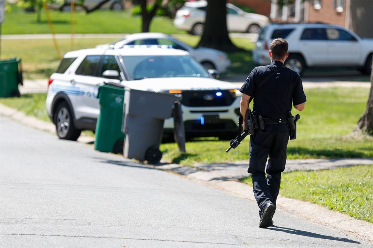 A Charlotte Mecklenburg police officer walks carrying a gun in the neighborhood where a shooting took place in Charlotte, North Carolina, Monday, April 29