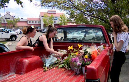 Three Lehi High School students getting flowers out of a truck bed to support the teacher who was hurt.