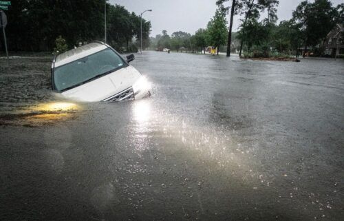 An SUV is stranded in a ditch along a stretch of street flooding during a severe storm Thursday in Spring