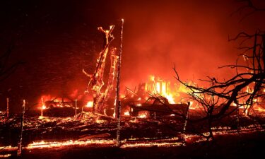 A structure and vehicles burn during the Corral Fire