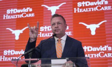 Jim Schlossnagle flashes a hook'em sign as he speaks at a news conference after he was introduced as the new NCAA college head baseball coach at Texas