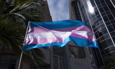 A transgender flag is seen waving during a gathering at City Hall in Orlando