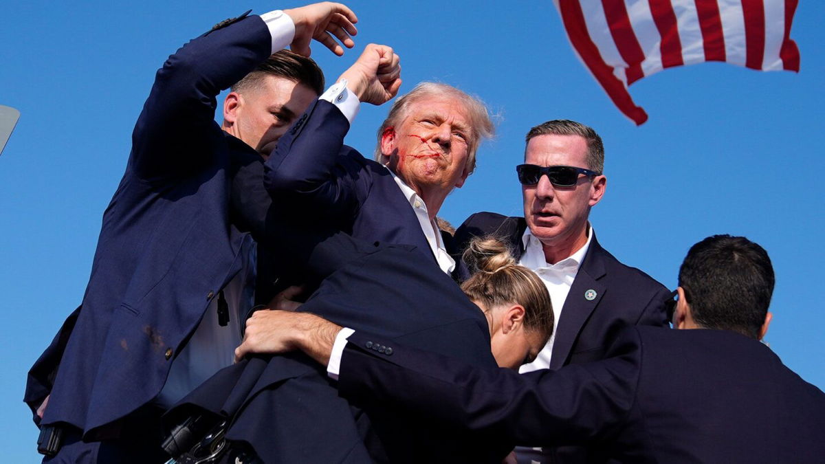 <i>Evan Vucci/AP via CNN Newsource</i><br/>Former President Donald Trump is surrounded by U.S. Secret Service agents after he was shot at a campaign rally on July 13