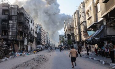 Palestinians rush towards a column of smoke billowing following Israeli bombardment which hit a school complex