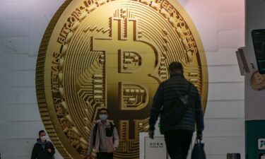 Pedestrians walk past an advertisement displaying a Bitcoin cryptocurrency token in February 2022 in Hong Kong