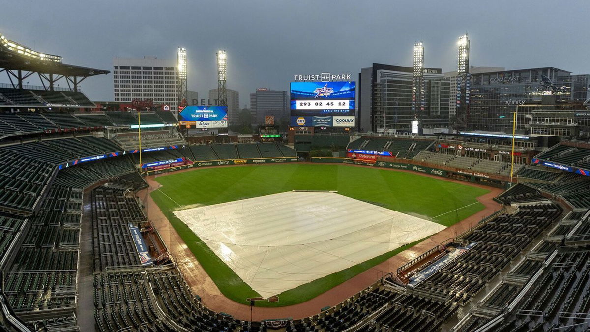 <i>Jason Allen/AP via CNN Newsource</i><br/>A tarp covers the infield as rain comes down at Truist Park in Atlanta after both September 25 and 26 New York Mets-Atlanta Braves games were postponed due to inclement weather.