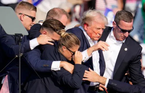 Former President Donald Trump is helped off the stage by US Secret Service agents at a campaign event in Butler