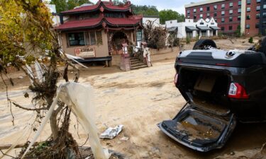 A sign commemorating the flood of 1916 lies on the ground next to a flooded waterway near Biltmore Village.