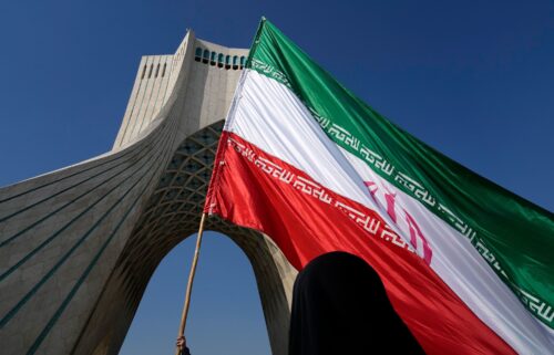 An Iranian flag is carried under the Azadi (Freedom) monument tower in Tehran