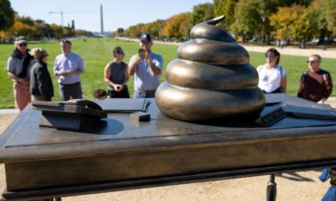 People look at a bronze art installation depicting a pile of feces on former US Speaker of the House Nancy Pelosi's desk on the National Mall near the US Capitol in Washington