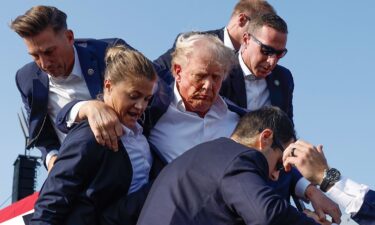 Republican presidential candidate former President Donald Trump is rushed offstage by US Secret Service agents after being grazed by a bullet during a rally on July 13