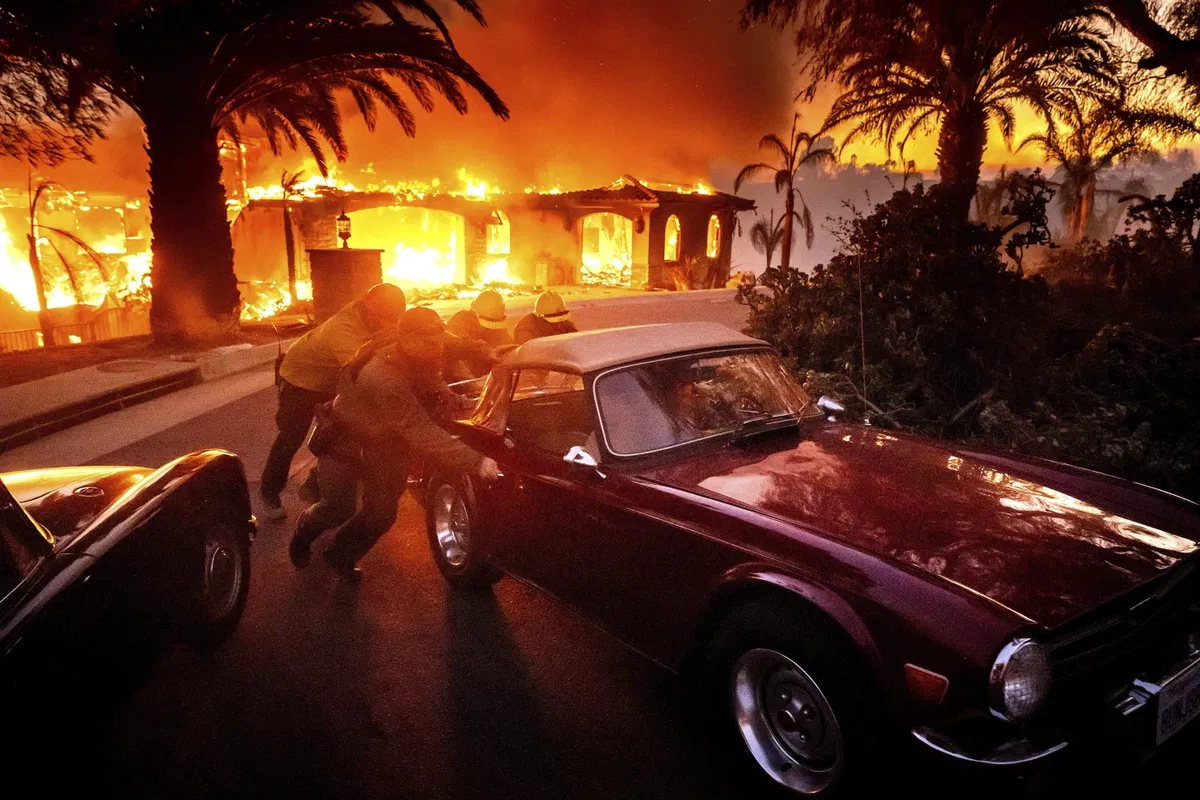 Firefighters and sheriff's deputies push away a vintage car away from a burning home as the Mountain Fire burns n Camarillo, Calif., on Wednesday, Nov. 6, 2024 (AP Photo/Noah Berger) 