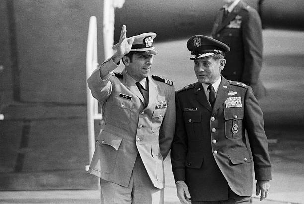 (Original Caption) Travis AFB, Calif.: Lt. Cdmr Everett Alvarez, Jr (L), USN, is escorted by Maj. Gen. John F. Gonge, CG, 22d Air Force, Mac. Alvarez, from Santa Clara, Calif., the longest-to-be-held POW in North Vietnam, is waving at large crowd assembled to greet the second planeload of POWs to arrive here 2/16. 2/16/1973. Getty Images