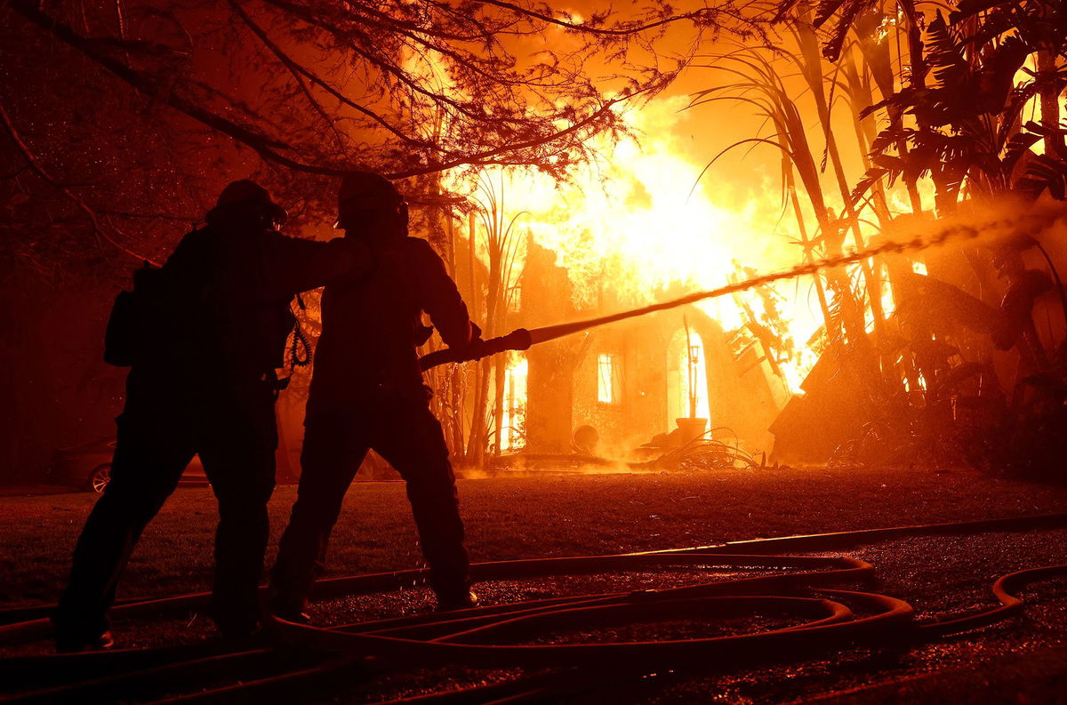 <i>Justin Sullivan/Getty Images via CNN Newsource</i><br/>Los Angeles County firefighters spray water on a burning home as the Eaton Fire moved through the area on January 8 in Altadena