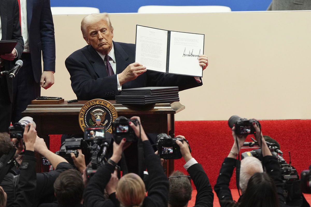 <i>Matt Rourke/AP via CNN Newsource</i><br/>President Donald Trump holds up an executive order after signing it at an indoor Presidential Inauguration parade event in Washington