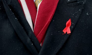 A participant with a red ribbon symbolizing the fight against the HIV virus takes part in a ceremony to mark World AIDS Day near a monument in memory of AIDS victims in Kiev