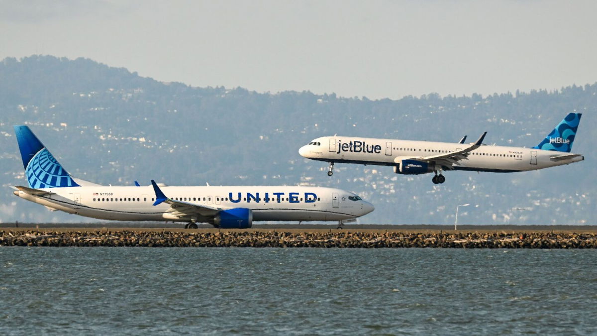 <i>Tayfun CoSkun/Anadolu/Getty Images/File via CNN Newsource</i><br/>A United Airlines plane prepares for takeoff as a JetBlue plane lands at San Francisco International Airport in 2023.
