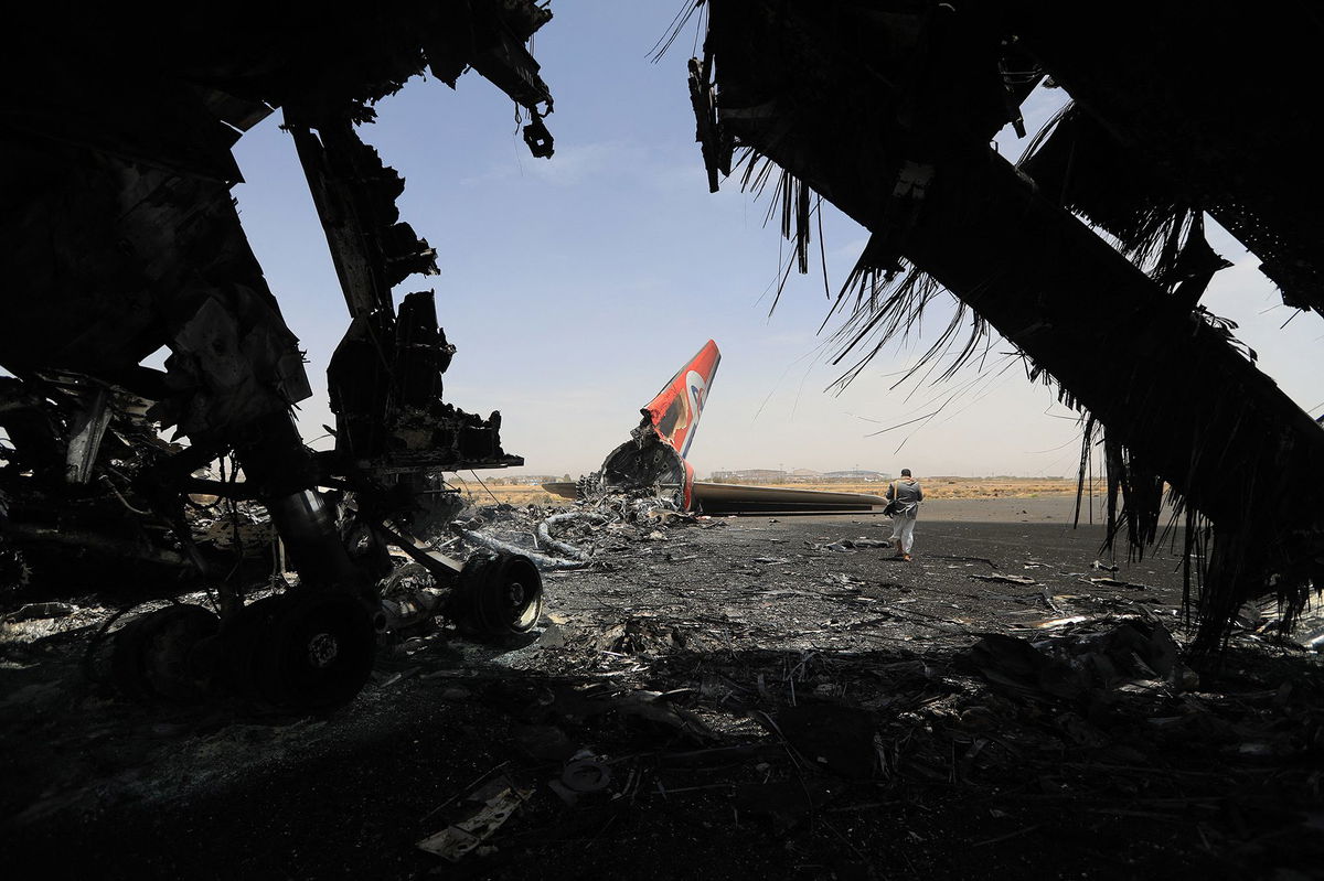 <i>Mohammed Huwais/AFP/Getty Images via CNN Newsource</i><br/>A Houthi rebel walks next to a destroyed plane at the Sanaa International Airport last month