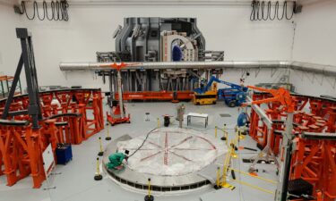 A person works on the cryostat base of the fusion reactor inside the tokamak hall at Commonwealth Fusion Systems in Devens