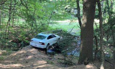 Christopher Shorey's Volvo got stuck on the narrow pedestrian bridge and broke through the wooden structure. His car wound up partially hanging off the bridge