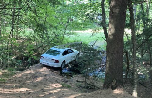 Christopher Shorey's Volvo got stuck on the narrow pedestrian bridge and broke through the wooden structure. His car wound up partially hanging off the bridge