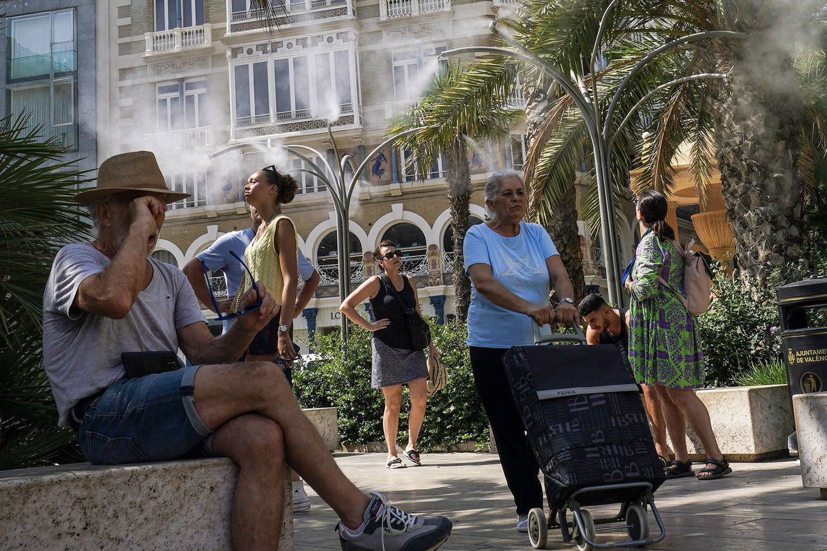 <i>Horacio Villalobos/Corbis News/Getty Images via CNN Newsource</i><br/>Pedestrians walk past a pharmacy sign showing 39 degrees celsius (86 Fahreneheit) as high temperatures hit Lisbon