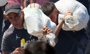 Palestinians seeking aid from the U.S.-backed Gaza Humanitarian Foundation carry bags