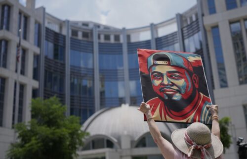 Katheryn Millwee holds a portrait of Kilmar Abrego Garcia outside the federal courthouse on June 25